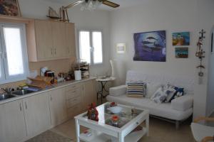 a living room with a white couch and a kitchen at MARINA apartment in Tinos Town