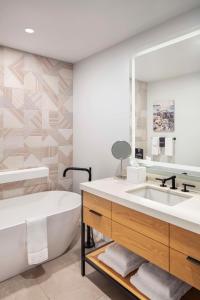 La salle de bains est pourvue d'une baignoire, d'un lavabo et d'un miroir. dans l'établissement Canopy By Hilton Portland Waterfront, à Portland