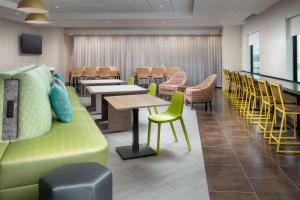 una sala de espera con mesas y sillas y un sofá verde en Home2 Suites by Hilton Orlando Downtown, FL, en Orlando