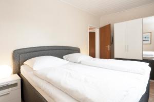 um quarto com uma grande cama branca com almofadas brancas em Haus Sonneninsel Wohnung 5 em Grömitz
