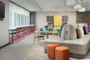 a waiting room with a couch and tables and chairs at Home2 Suites By Hilton Tampa Westshore Airport, Fl in Tampa