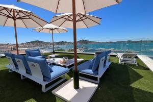 une terrasse avec des chaises et des parasols bleus et l'eau dans l'établissement Murter Luxury Penthouse with Sea View for two, à Murter