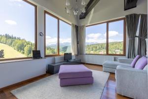 a living room with large windows and purple furniture at Vila Etiquette in Predeal