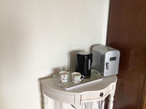 a coffee maker and two cups on a table at Océan Waves in Gorleston-on-Sea