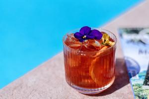 a drink sitting on a table with a purple flower in it at Bella Hotel & Restaurant with private dock for mooring boats in San Felice del Benaco