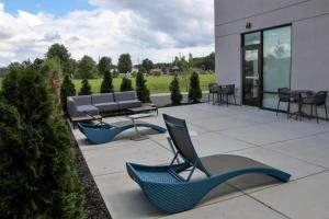 un patio avec des chaises, un banc et des tables dans l'établissement Hampton Inn & Suites Olean, Ny, à Olean
