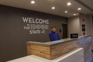 a man is standing at a welcome to the empire state at Hampton Inn & Suites Olean, Ny in Olean