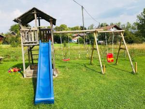 a playground with a blue slide and swings at Ferienhaus Sommer in Pfronten