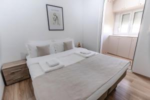 ein weißes Schlafzimmer mit einem großen Bett mit weißer Bettwäsche in der Unterkunft RoofTop in Aranđelovac