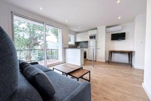 a living room with a gray couch and a kitchen at CAN ROMY APPARTEMENT T3 B - à 20m de la plage de Cala Montgo in L'Escala