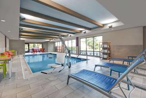 Home2 Suites by Hilton Blacksburg University في بلاكسبورغ: مسبح مع كراسي ومرجيح في مبنى