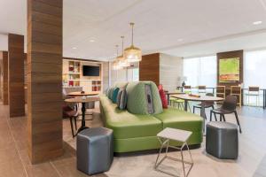 uma sala de estar com um sofá verde e mesas em Home2 Suites By Hilton West Sacramento, Ca em West Sacramento