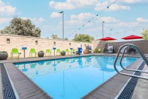 - une piscine avec des chaises longues et des parasols dans l'établissement Home2 Suites By Hilton West Sacramento, Ca, à West Sacramento