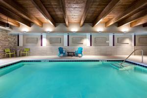 uma piscina com cadeiras azuis e mesas e cadeiras em Home2 Suites By Hilton Lincolnshire Chicago em Lincolnshire