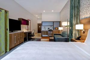 リンカーンシャーにあるHome2 Suites By Hilton Lincolnshire Chicagoのベッド、デスク、テレビが備わるホテルルームです。