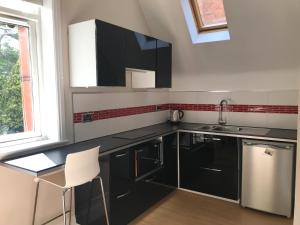 a kitchen with black cabinets and a sink and a window at Glenlyon Flat - NEC in Hampton in Arden