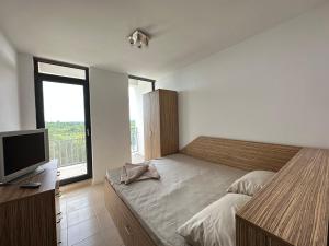 a bedroom with a bed and a flat screen tv at Apartament Oxygen in Neptun