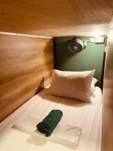 a bed with a wooden headboard and a green pillow at Oasis Hostel Medellin in Medellín