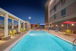 a swimming pool with tables and chairs and a building at Home2 Suites By Hilton Phoenix Avondale, Az in Avondale