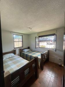 a bedroom with two beds and two windows at Finca Colonial / Lago Calima in Calima