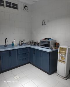 a kitchen with blue cabinets and a microwave and a refrigerator at شقه كلاسك ثلاث غرف in Jeddah