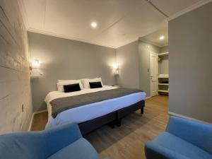 1 dormitorio con 1 cama y 2 sillas azules en Hostal Boutique Puerta Roja, en Punta Arenas