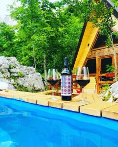 dois copos de vinho numa mesa ao lado de uma piscina em Etno apartmani Komarnica em Šavnik
