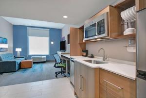 a kitchen with a sink and a living room at Home2 Suites By Hilton Bentonville Rogers in Bentonville