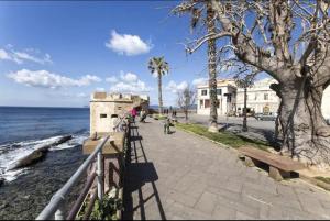 una acera junto al océano con palmeras en Apartment Cavour, en Alghero