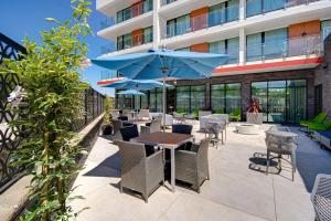 Hampton Inn & Suites Sunnyvale-Silicon Valley, Ca في سانيفيل: فناء به طاولات وكراسي ومظلة