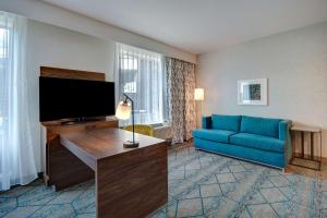 Hampton Inn & Suites Sunnyvale-Silicon Valley, Ca في سانيفيل: غرفة معيشة مع أريكة زرقاء وتلفزيون بشاشة مسطحة