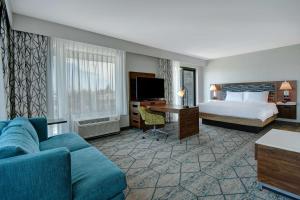 Hampton Inn & Suites Sunnyvale-Silicon Valley, Ca في سانيفيل: غرفه فندقيه بسرير واريكه