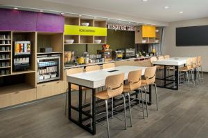 Home2 Suites By Hilton Kenner New Orleans Arpt في كينير: مطبخ مع طاولتين وكراسي في مخزن