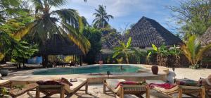 a pool at a resort with chairs and palm trees at Mpole Bungalows in Michamvi