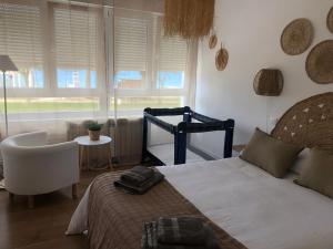 a bedroom with a bed and a chair and a window at Apartamento Comillas Beach in Comillas