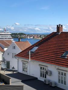 a white building with red roofs and a cruise ship at Olav Kyrres Gate 39 2 etg 4 soverom ved taket av Stavanger in Stavanger