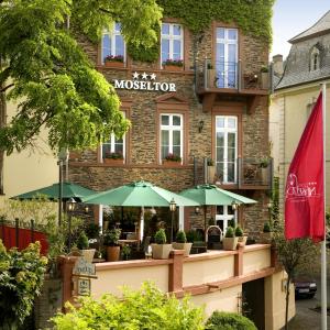 ein Restaurant mit grünen Sonnenschirmen vor einem Gebäude in der Unterkunft Boutique-Hotel Moseltor & Altstadt-Suiten in Traben-Trarbach