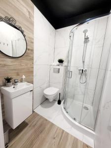 y baño con ducha, aseo y lavamanos. en Mini Apartamenty Poznań, en Poznan