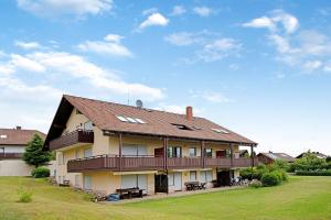 ein großes Haus mit einer Terrasse auf einem Rasen in der Unterkunft Ado Ferienwohnung in Grafenhausen