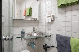 a white tiled bathroom with a sink and a shower at Ado Ferienwohnung in Grafenhausen +22 photos