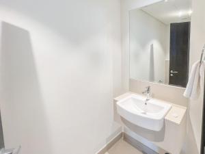a white bathroom with a sink and a mirror at Cosmos Living - Dubai Creek Harbour in Dubai