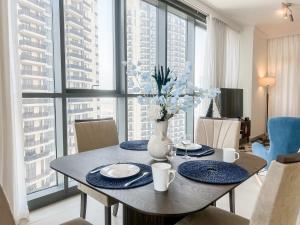 a dining room table with blue plates and a vase with flowers at Cosmos Living - Dubai Creek Harbour in Dubai