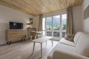 - un salon avec un canapé, une télévision et une table dans l'établissement Résidence Les Périades, à Chamonix-Mont-Blanc