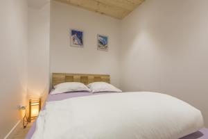 - une chambre avec un lit blanc et deux photos sur le mur dans l'établissement Résidence Les Périades, à Chamonix-Mont-Blanc