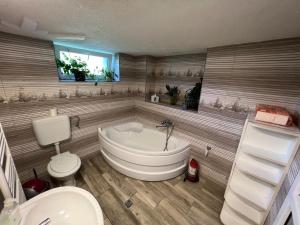 a bathroom with a tub and a toilet and a sink at HuniHáz Apartman in Sovata +20 photos