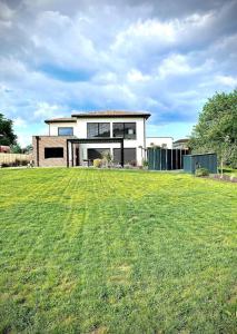 una casa en un patio con un gran campo de césped en Villa haut de gamme dans un parc de verdure, en Tournefeuille