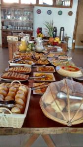 una mesa larga con muchos platos de comida. en Pousada Areia Preta, en Cumuruxatiba