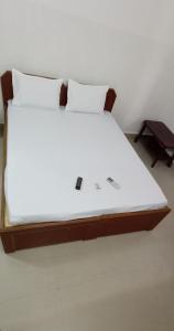 a bed with white sheets and pillows in a room at Chennai Guest House in Chennai