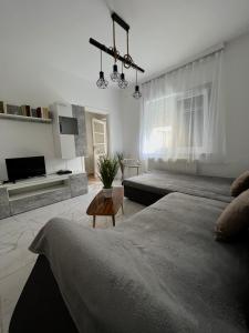 a white bedroom with a large bed and a table at AranyLak vendégház in Abádszalók