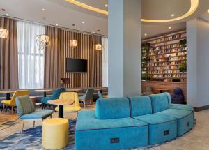 a lobby with a blue couch and chairs and a tv at Hampton By Hilton Tashkent in Tashkent